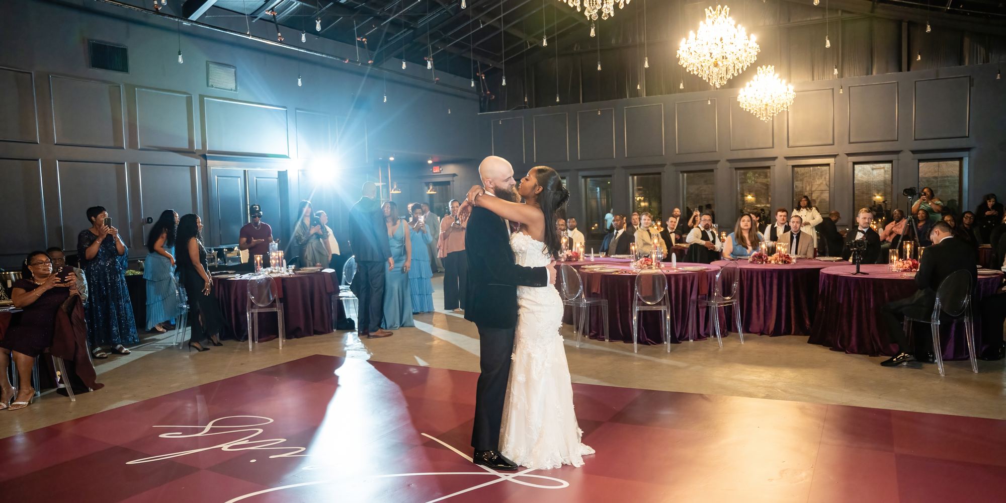 Wedding reception with chandeliers and a couple's first dance