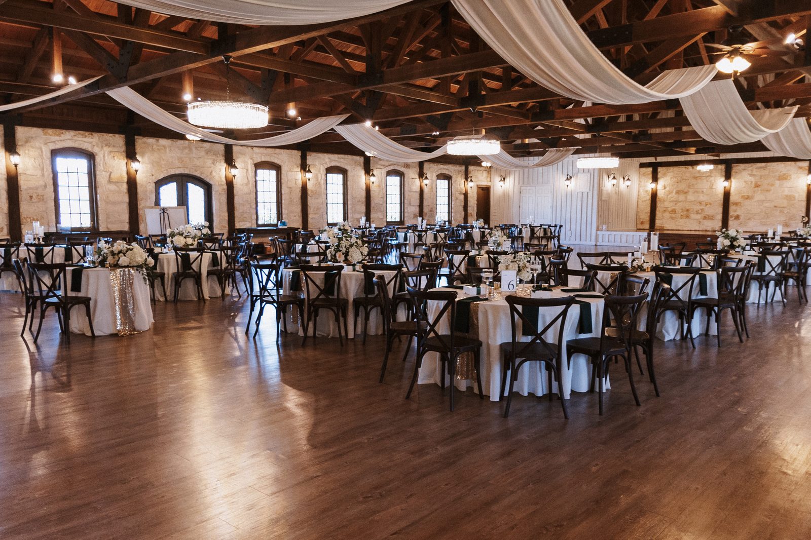 Elegant reception hall set with round tables, floral centerpieces, and warm chandeliers