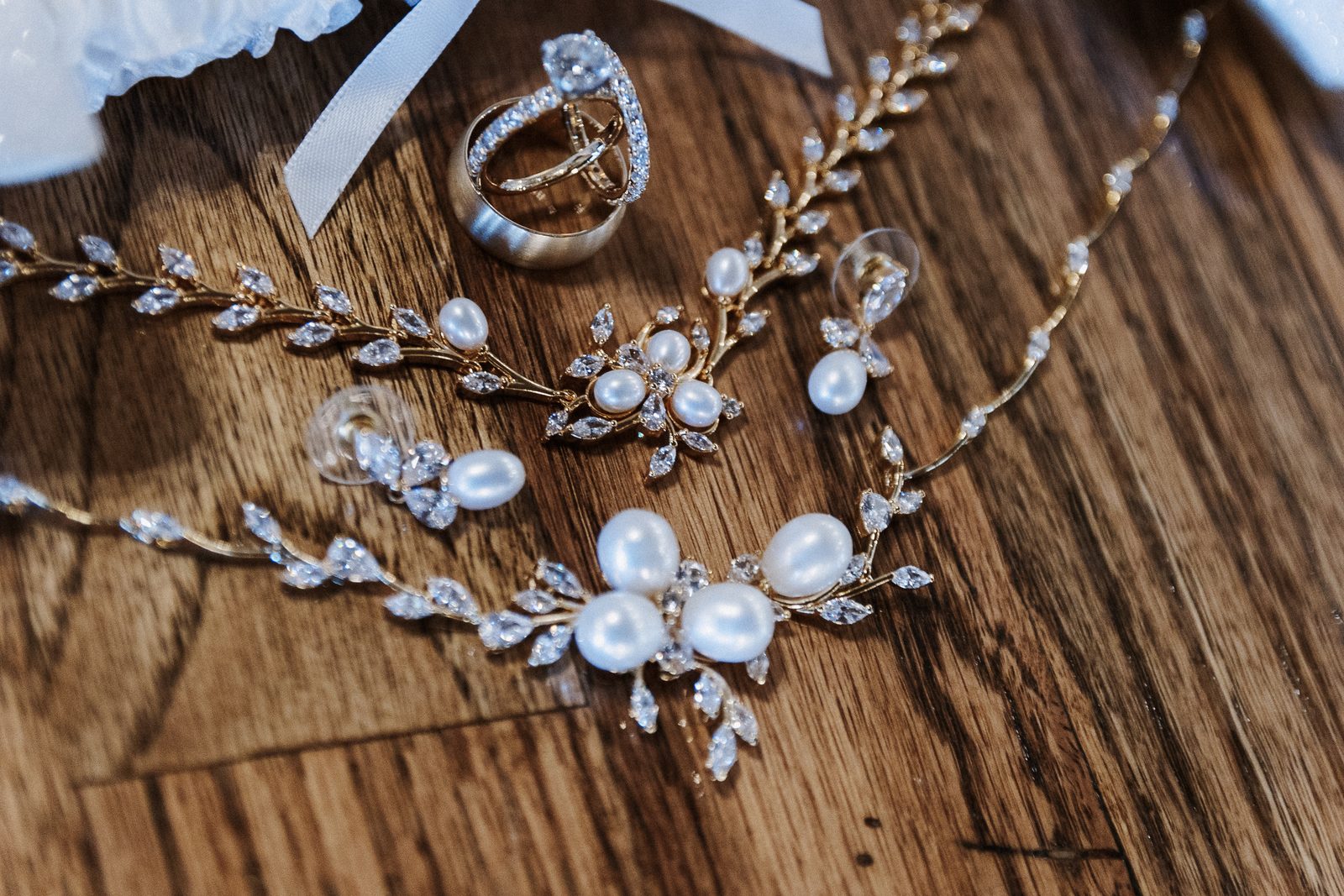 Wedding rings, pearl necklace and earrings on a wooden surface