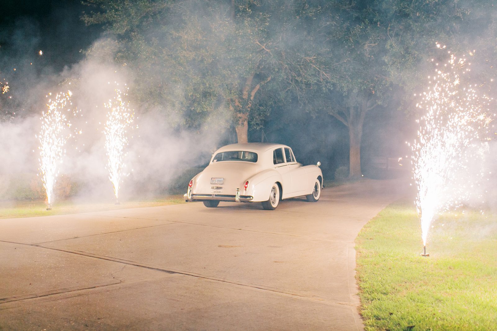 The couple's vintage getaway car driving off through fireworks