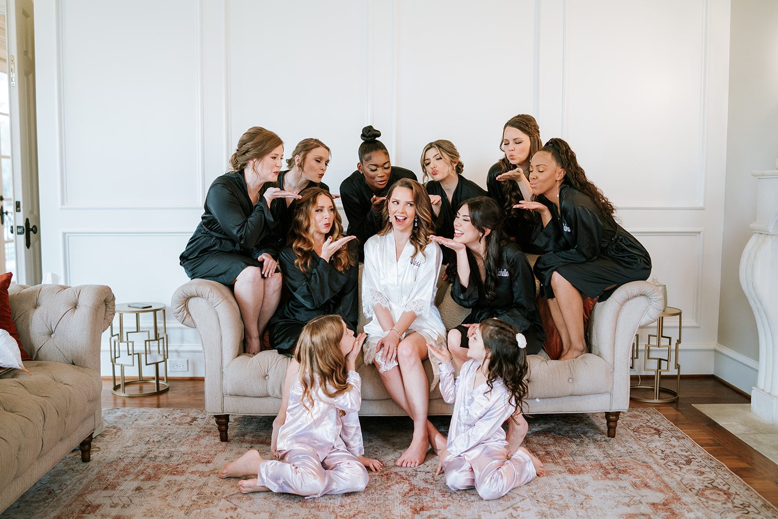 Bridesmaids and flower girls surrounding Alyssa on a couch, blowing kisses