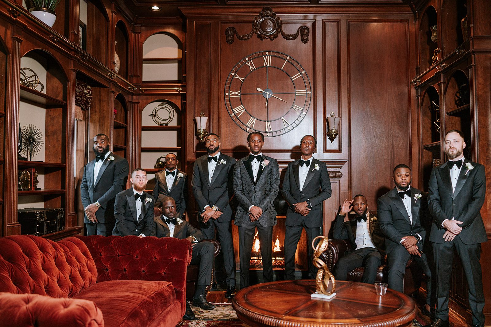 Eniola and groomsmen in a wood-paneled room by the fireplace