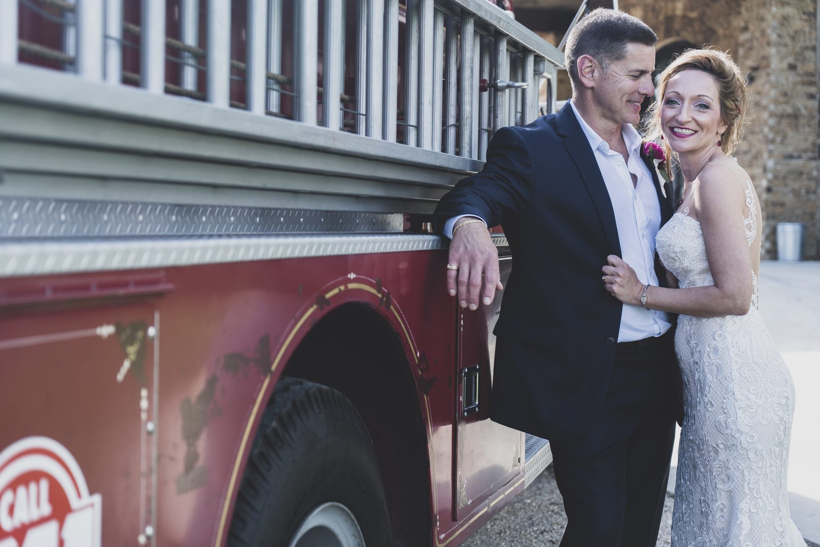 Carrie and Tony embracing by a vintage fire truck