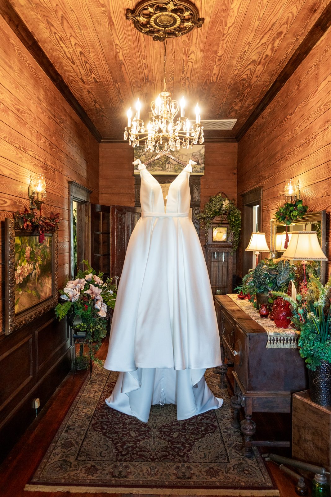 De's wedding dress hanging in a wood-paneled room