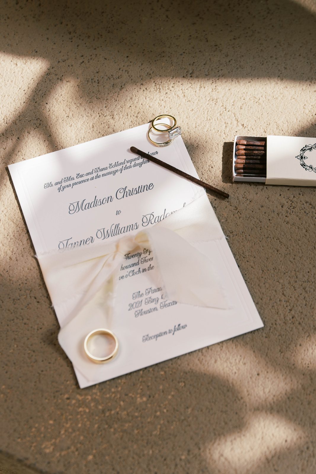 Wedding invitation with rings and a matchbox, sunlit detail shot