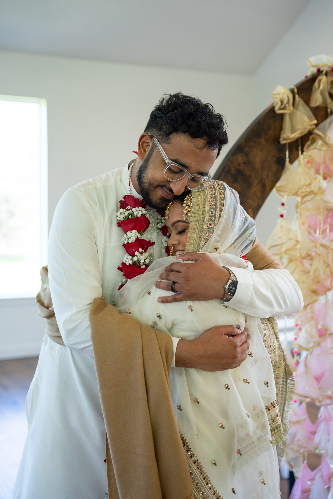 Maria and Mehrose embracing, wearing floral garlands