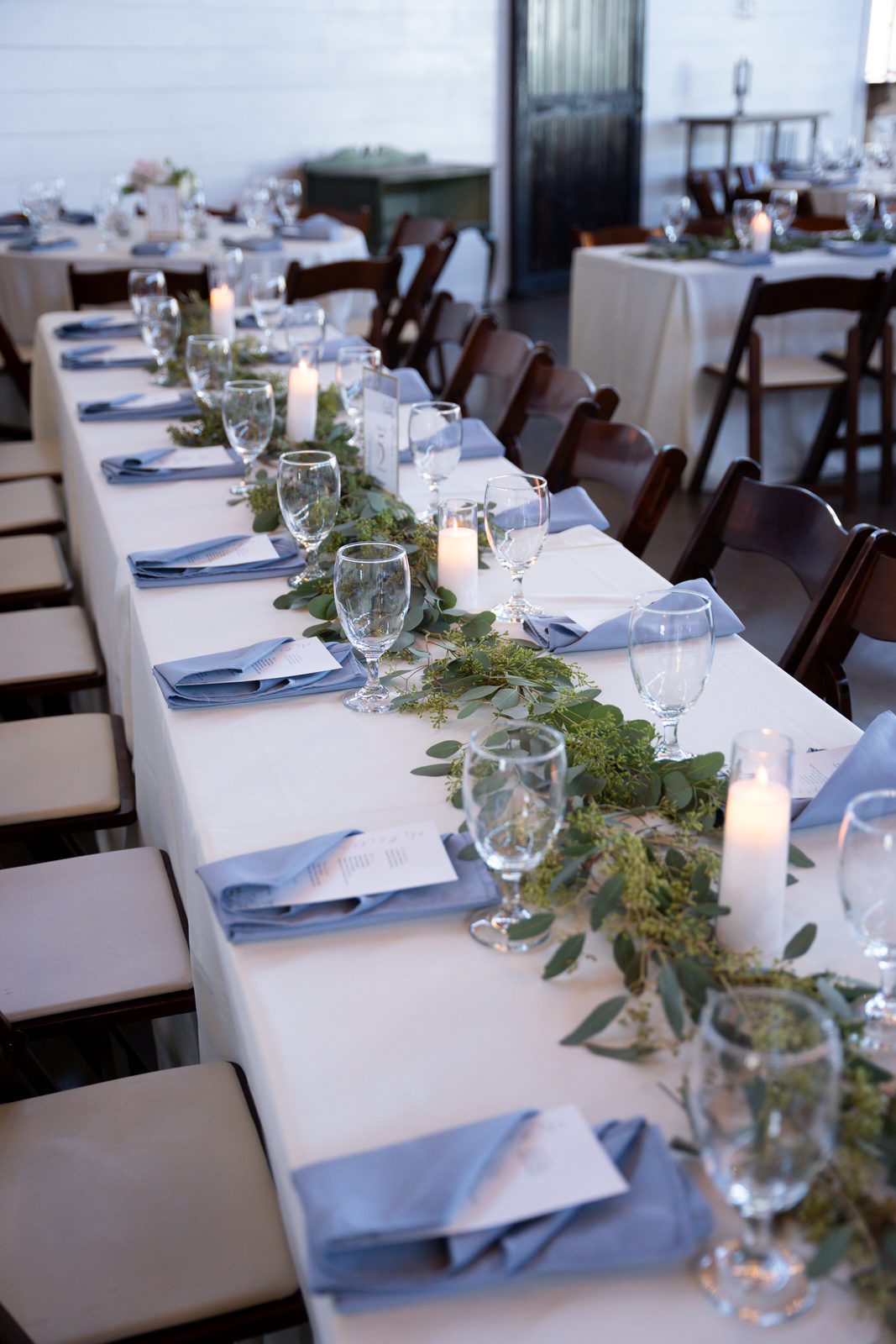 Reception table set with blue napkins and eucalyptus garland