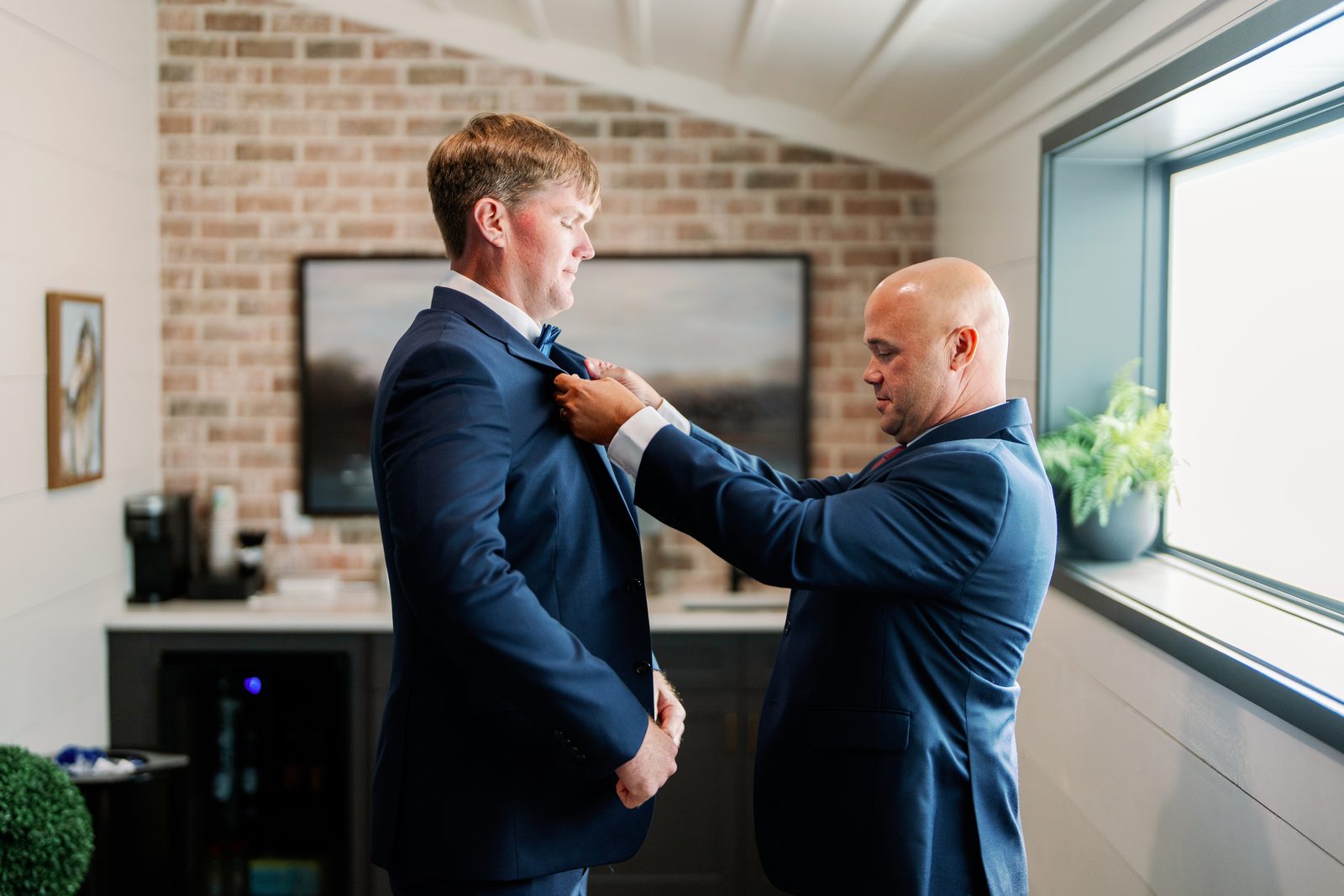 Groomsman buttoning David's suit jacket