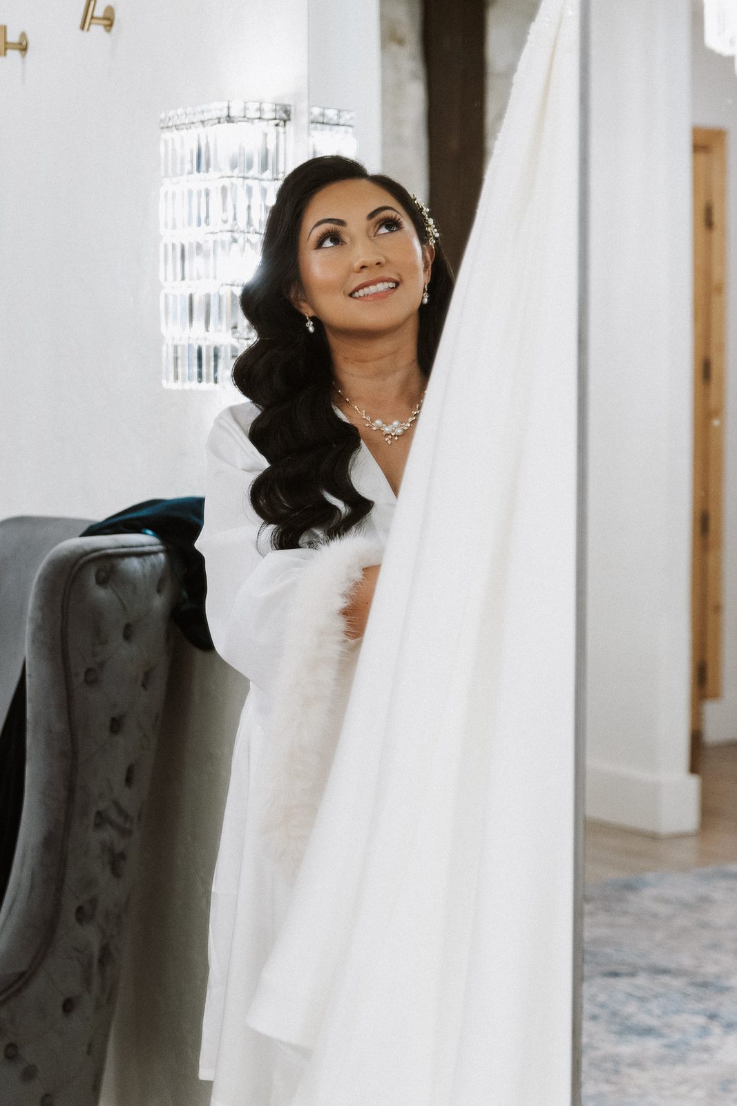Perla behind a sheer curtain, smiling and looking up