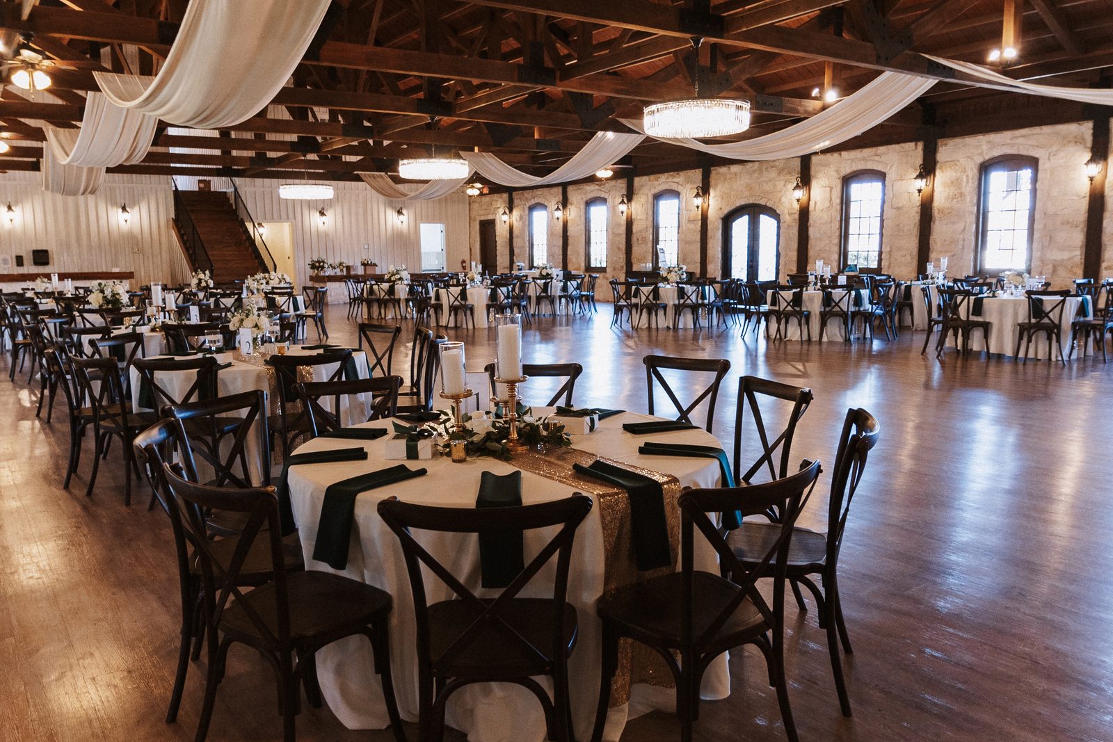 Reception hall set for dinner, with staircase and draped ceiling