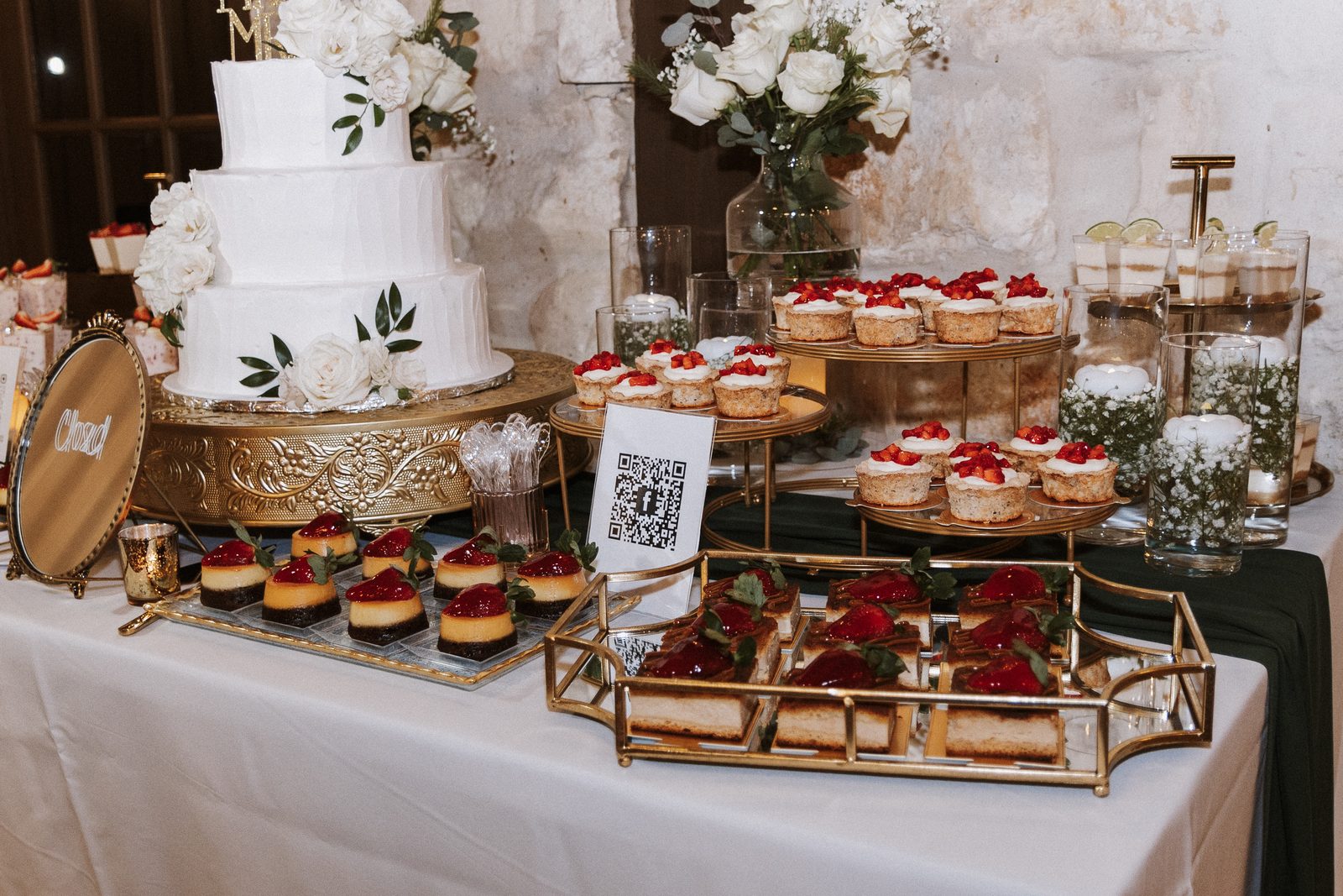 Dessert table with wedding cake, cupcakes, and cheesecake bites