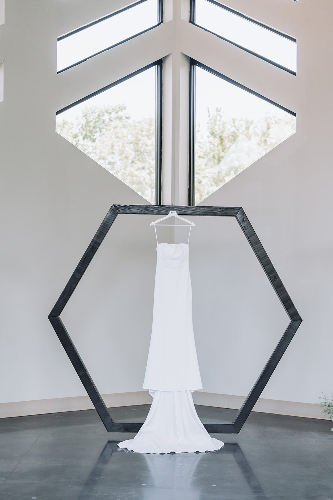 Sara's wedding dress hanging in a wooden hexagon frame